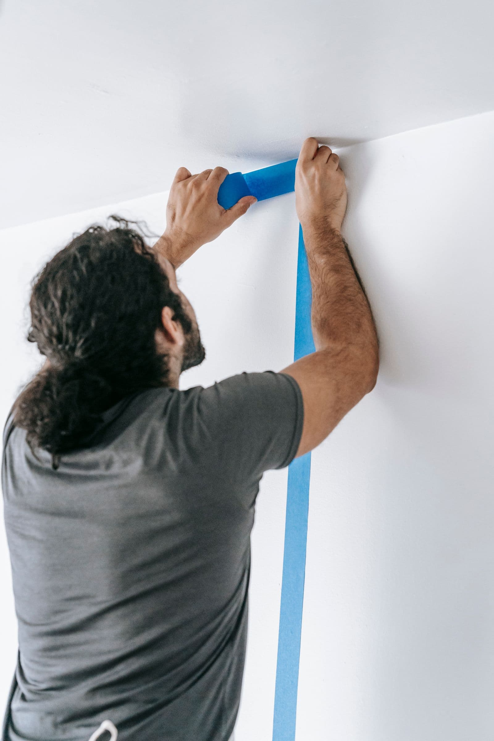 Pintor aplicando pintura con rodillo en el salón de un piso de Bilbao