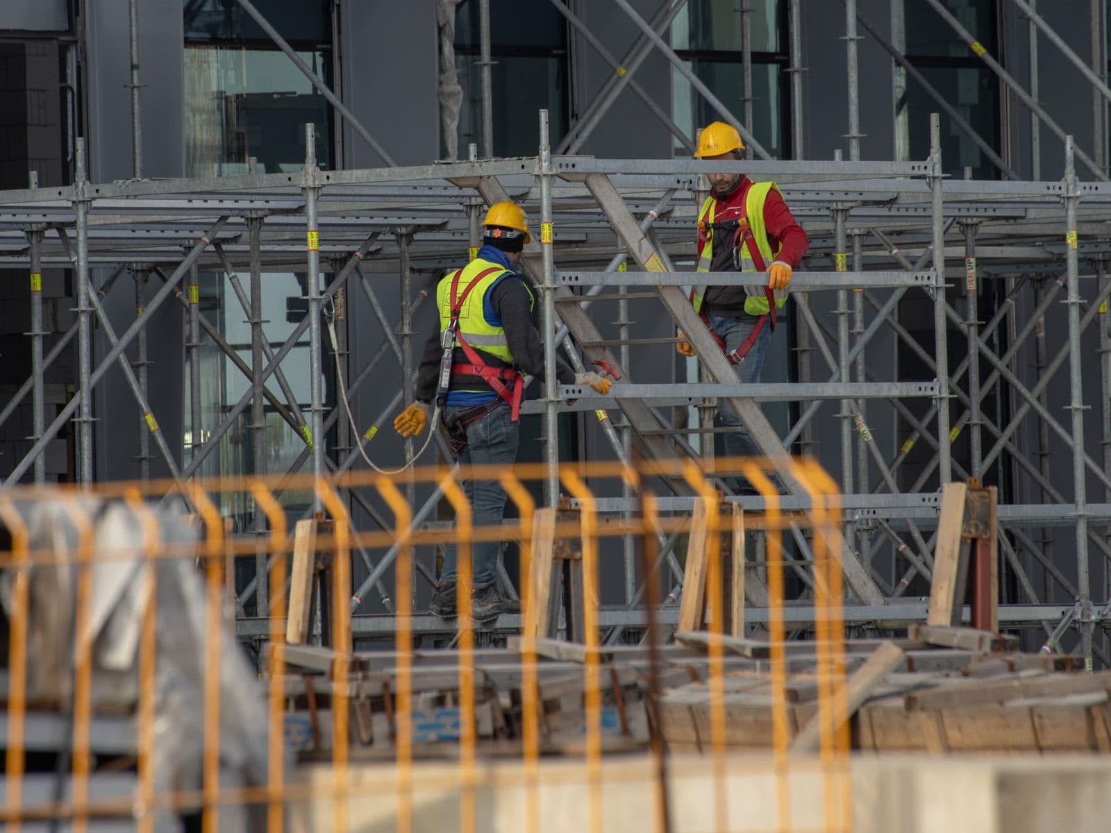 Equipo de pintores con casco y arnés trabajando en andamio sobre una fachada en Bilbao